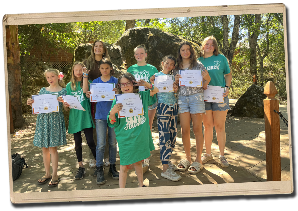 a group of campers posing outdoors with award certificates