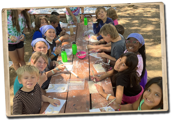 campers enjoying arts and crafts on a long picnic table